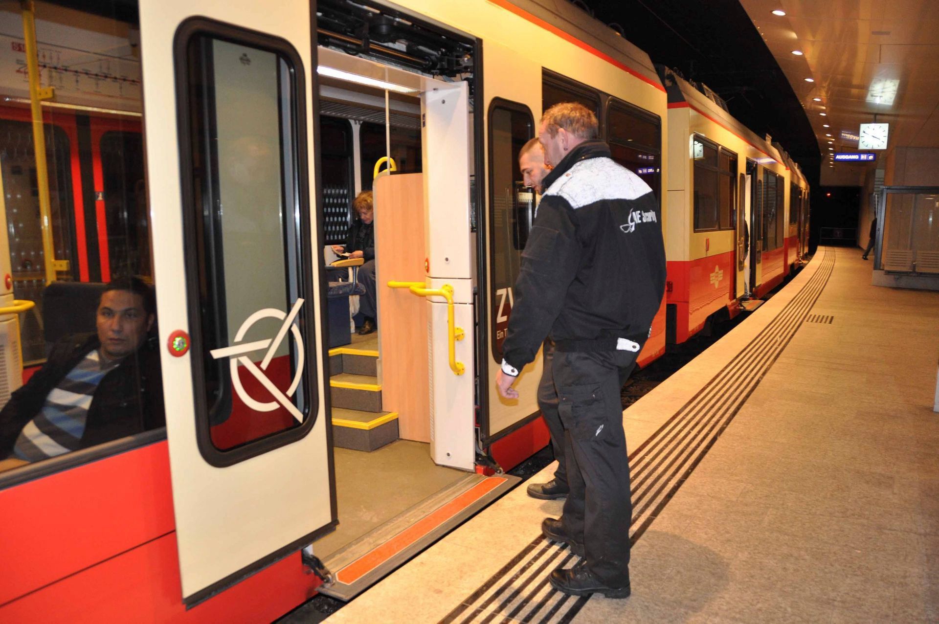 Ein Fahrgast besteigt nachts an einem Bahnsteig einen rot-weißen Zug.