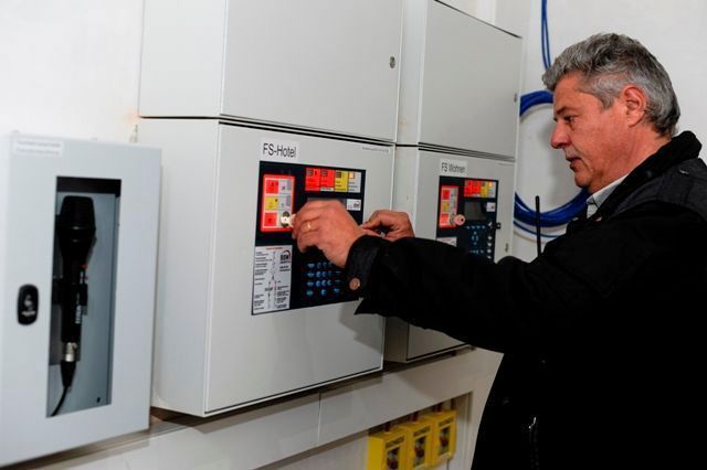 Ein Mann bedient ein an der Wand montiertes Bedienfeld mit digitalen Anzeigen in einem Hauswirtschaftsraum.