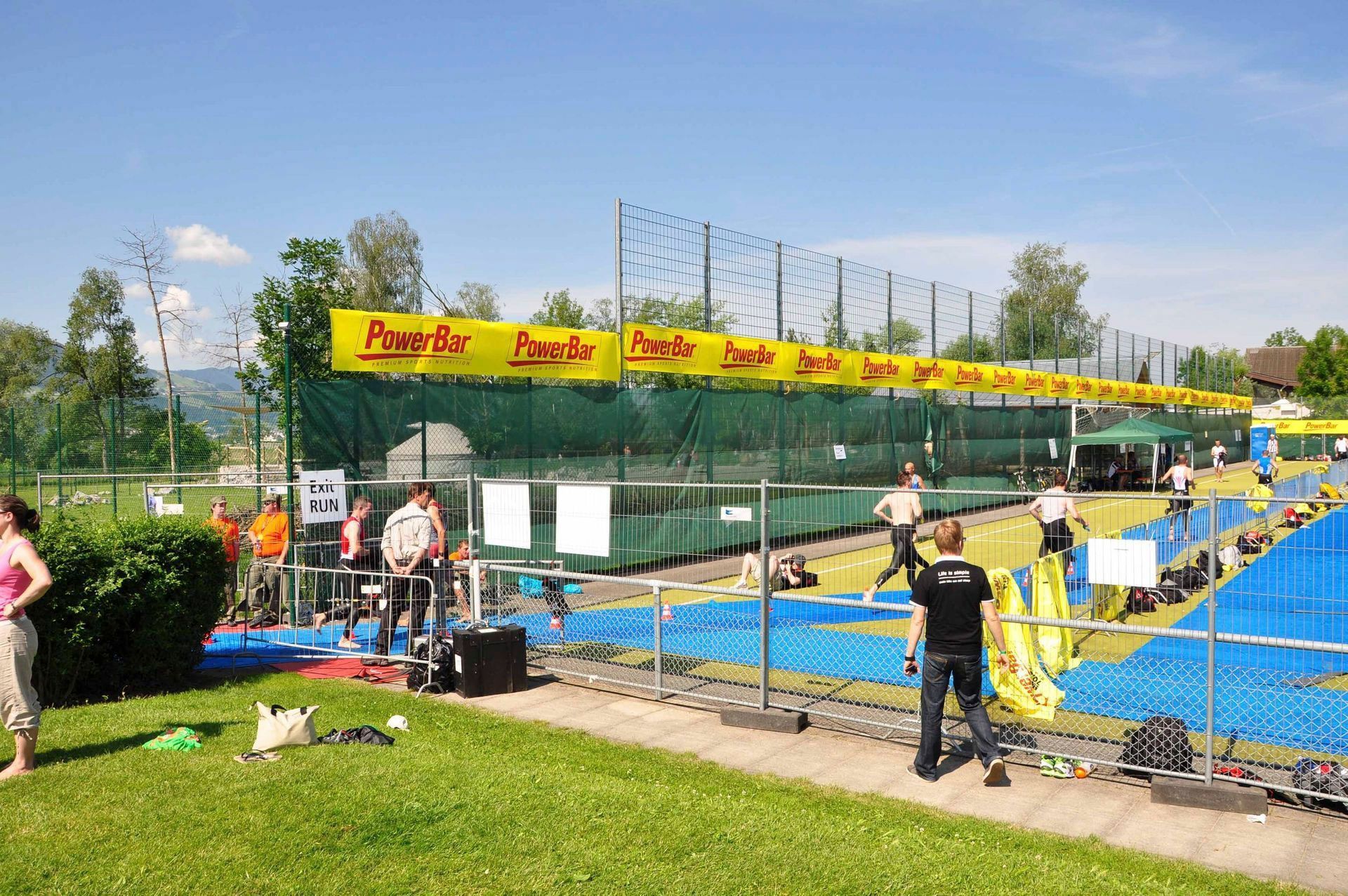Im Freien auf einer Minigolfanlage mit leuchtend blauen Bahnen, gelben Absperrungen und Menschen