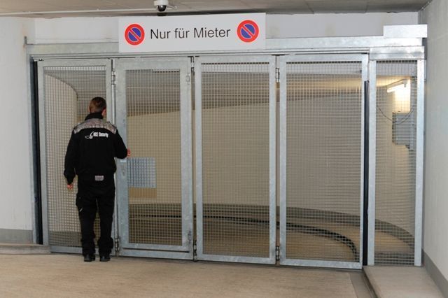 Guard at a glass entrance labeled “Nur für Mieter” in a building lobby