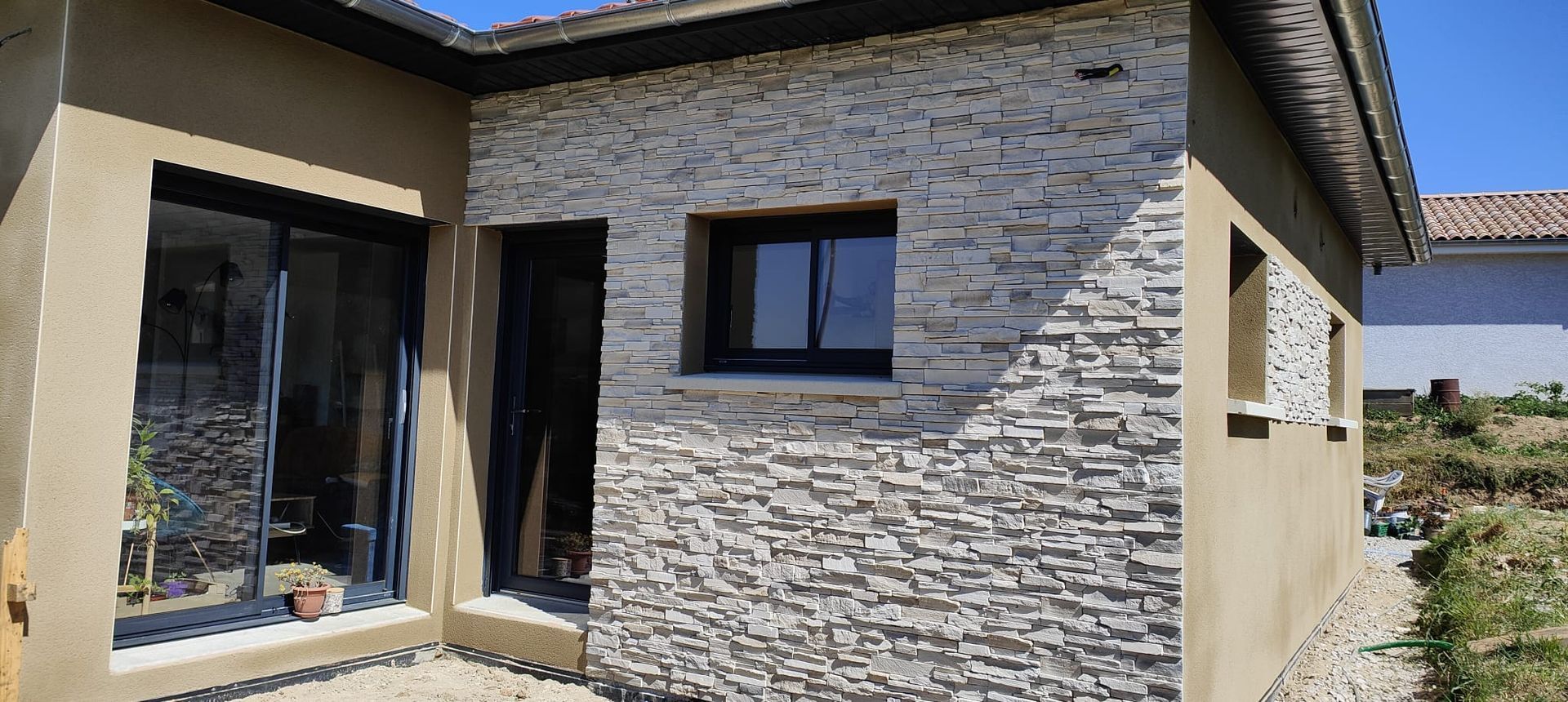 Une maison avec une partie de la façade en pierres apparantes 