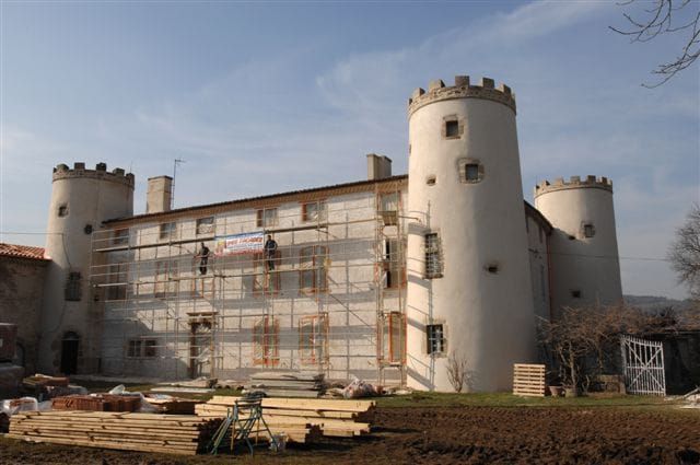 Deux personnes sur un échaffaudage sur la façade d'un chateau 