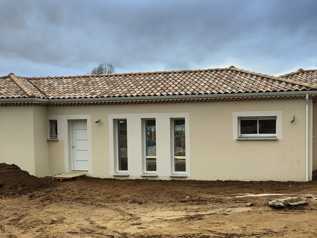 Des mains gantées posent un bloc de béton sur un mur avec du mortier.