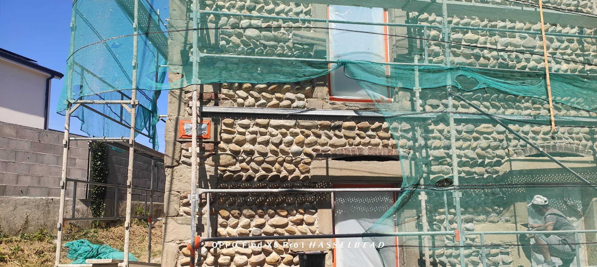 Maison à l'extérieur gris foncé avec deux fenêtres à cadre blanc sous un ciel bleu.