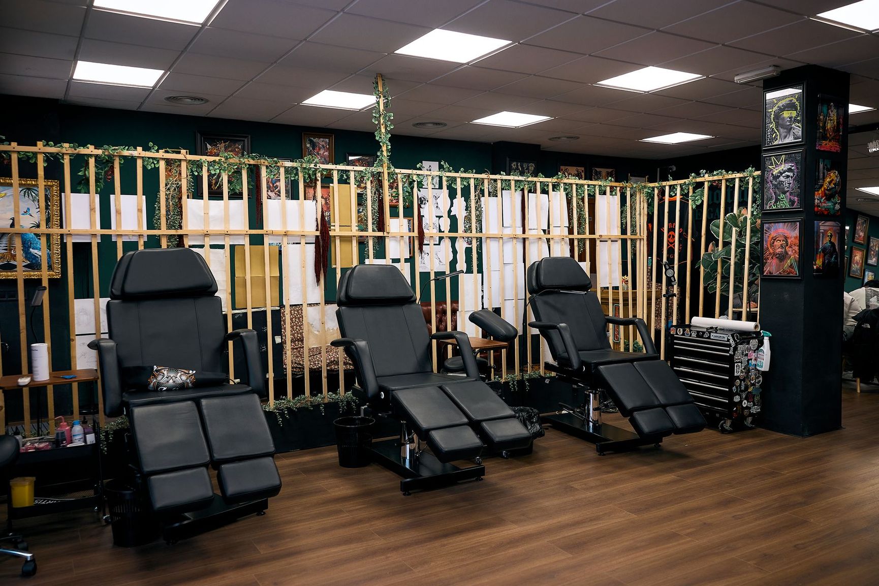 Sillones de masaje alineados en una sala de spa con poca luz, suelo de madera y decoración de bambú.
