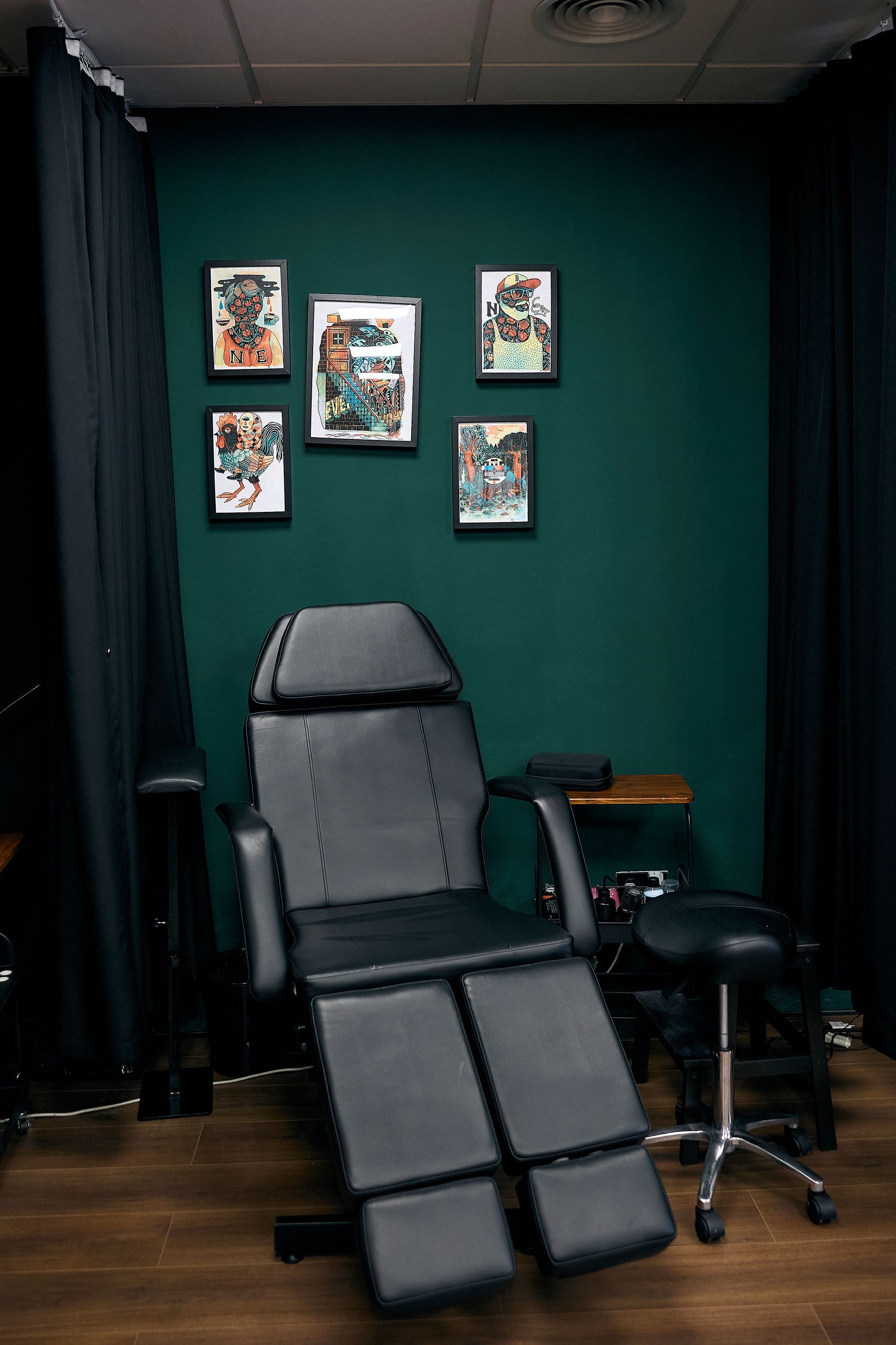 Sillón reclinable gris en una habitación verde oscuro con fotos enmarcadas en la pared y un taburete al lado.