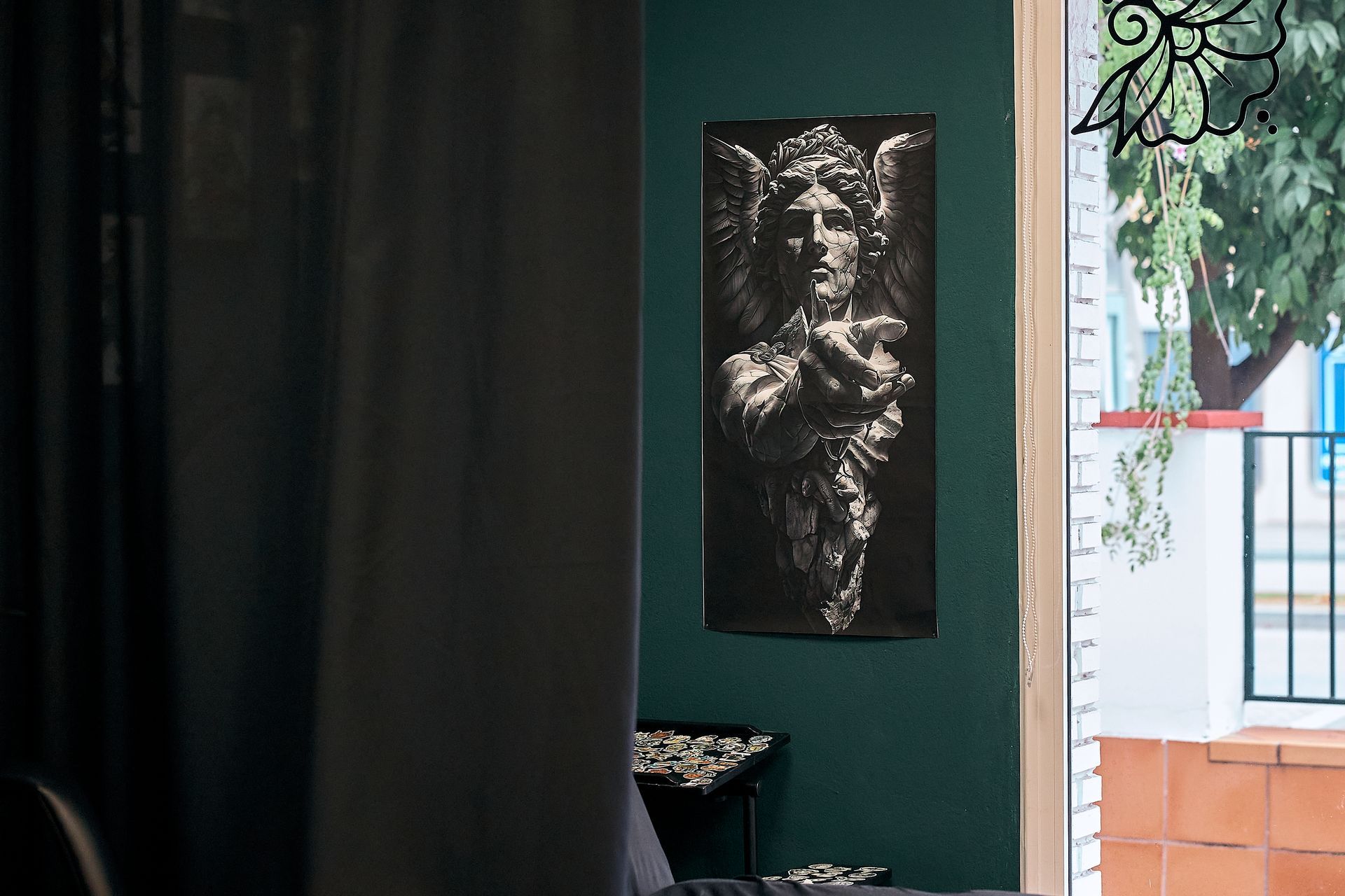 Habitación color turquesa con cortinas oscuras y un retrato en blanco y negro en la pared cerca de una ventana luminosa.