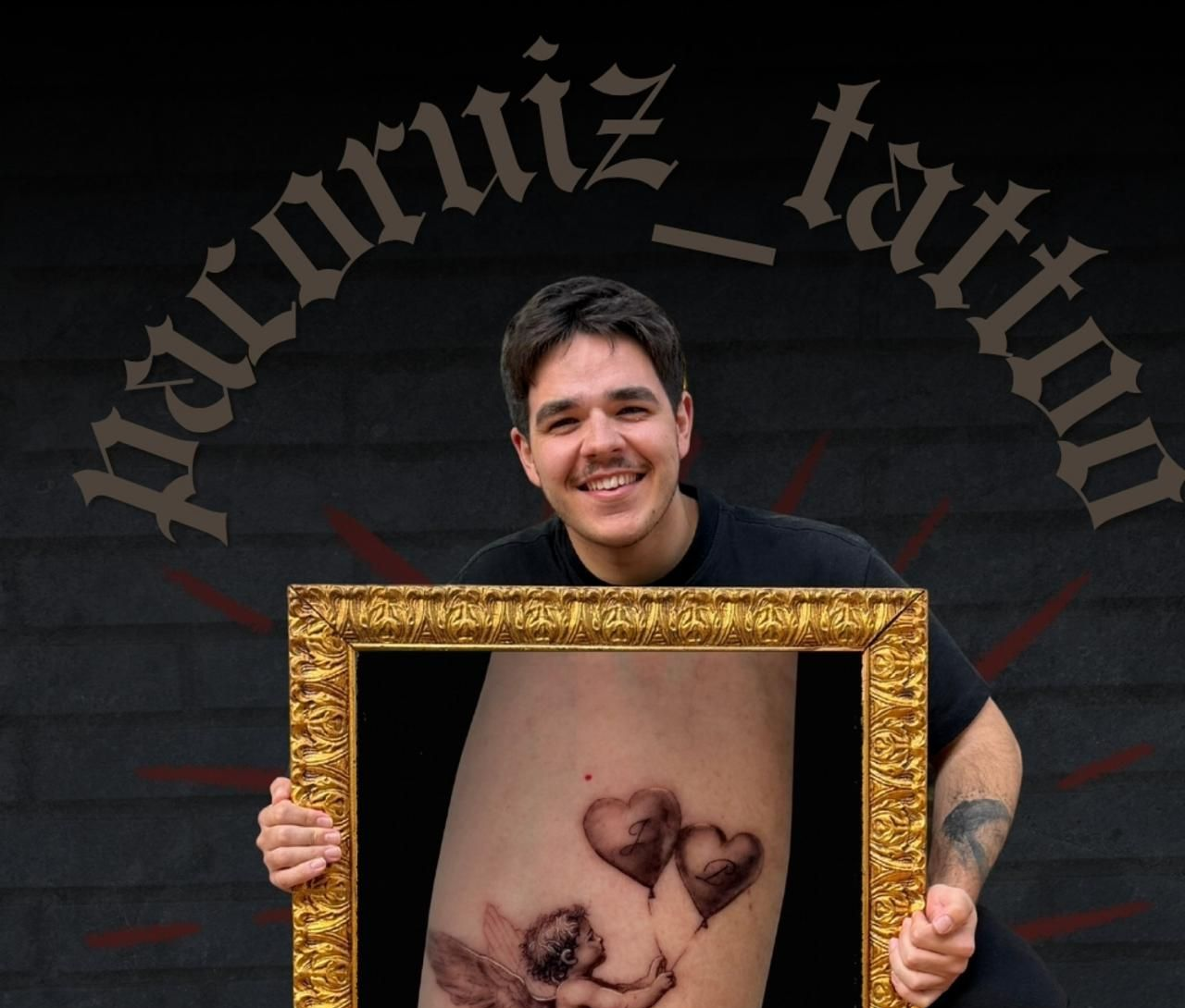 Una persona sonríe y sostiene un marco dorado sobre un antebrazo tatuado, con una pared oscura de fondo.