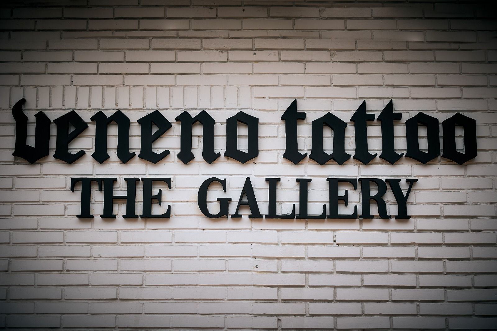 Una pared de ladrillo blanco con un letrero negro en 3D que dice 