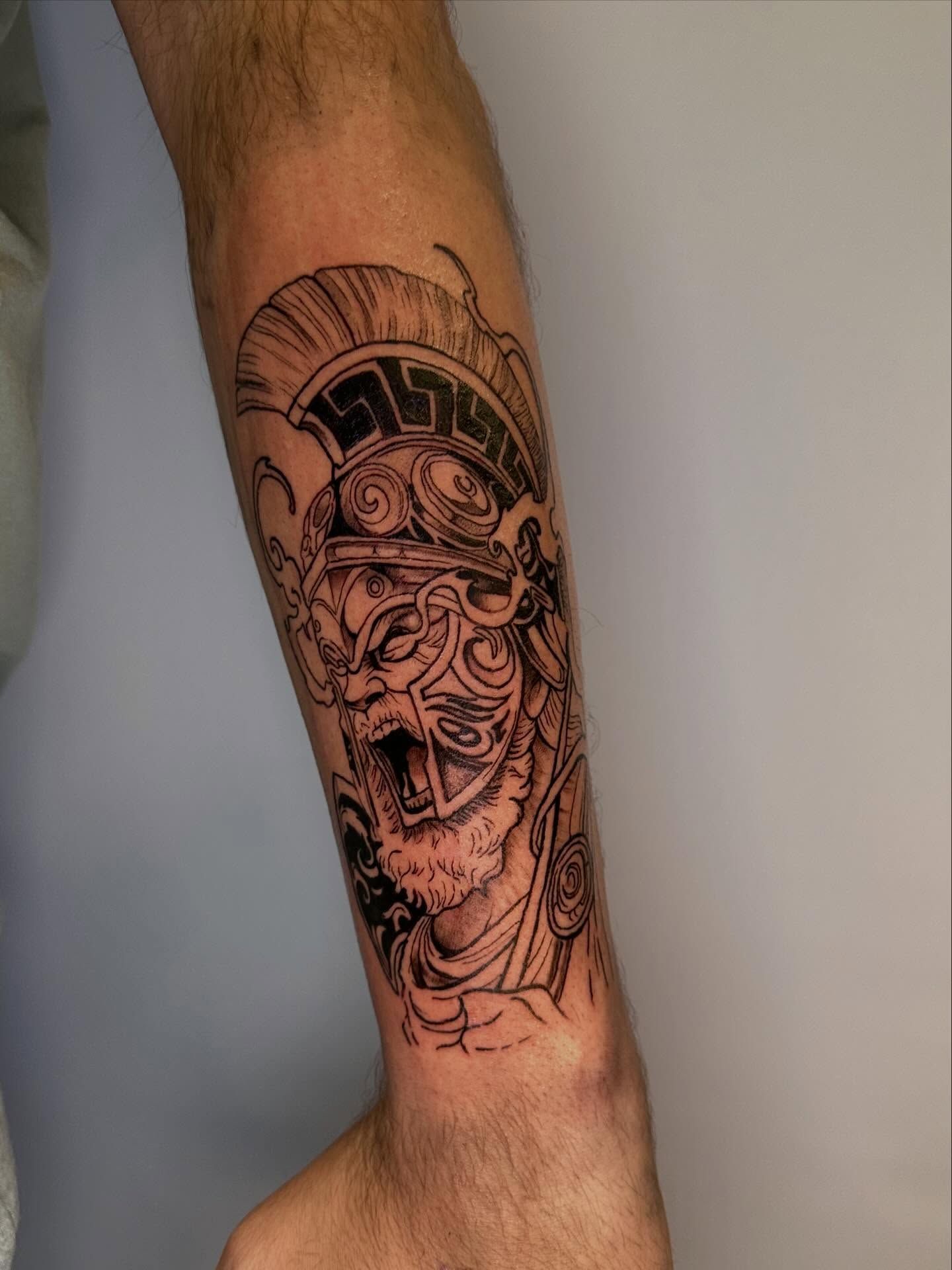 Un tatuaje en el antebrazo de un guerrero con un casco de estilo griego