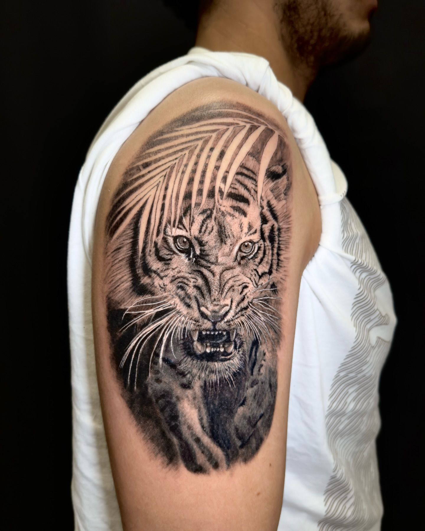 Un tatuaje un tigre asomándose entre hojas de palmera.