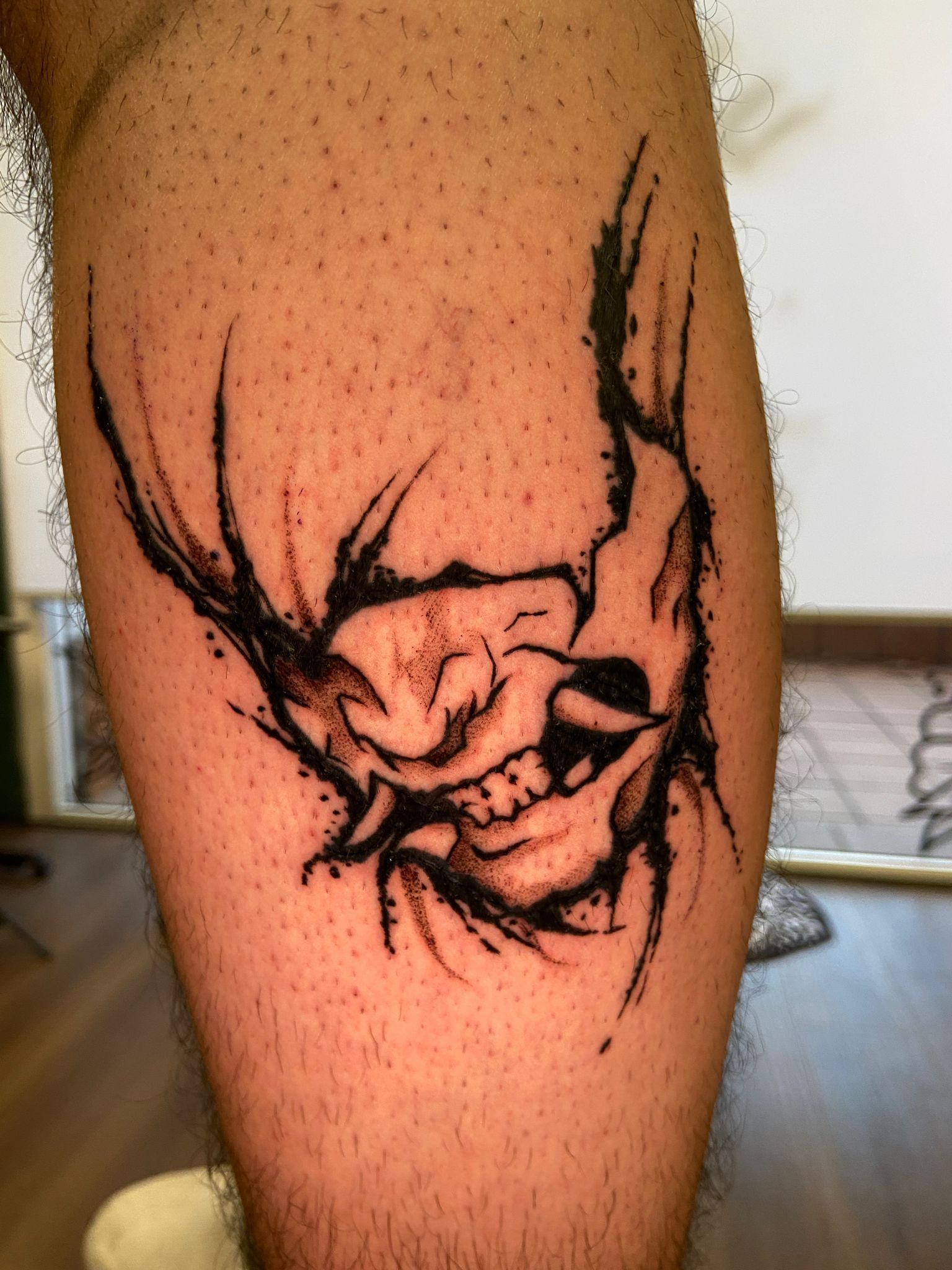 Primer plano de un tatuaje facial de estilo tribal negro en una pantorrilla.