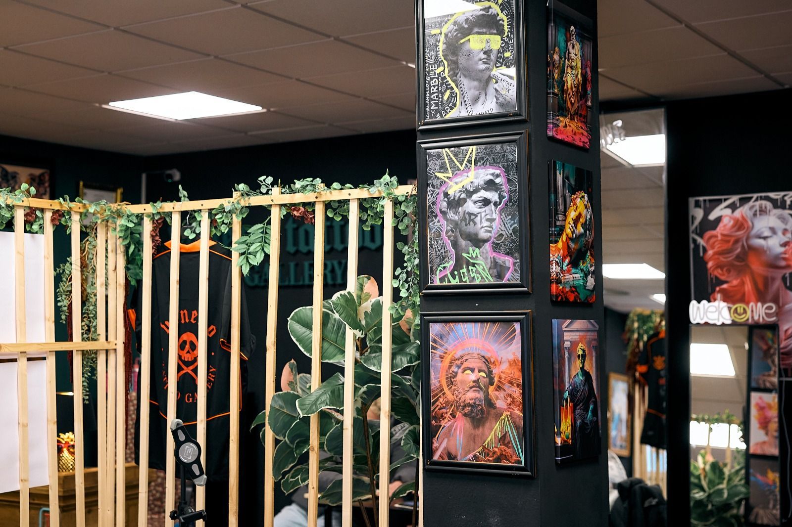 Un pilar oscuro exhibe tres láminas enmarcadas de estatuas clásicas