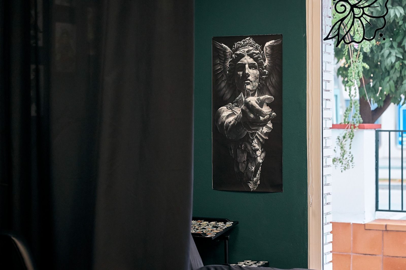 Un póster con una ilustración de alto contraste de un ángel sobre una pared verde oscuro