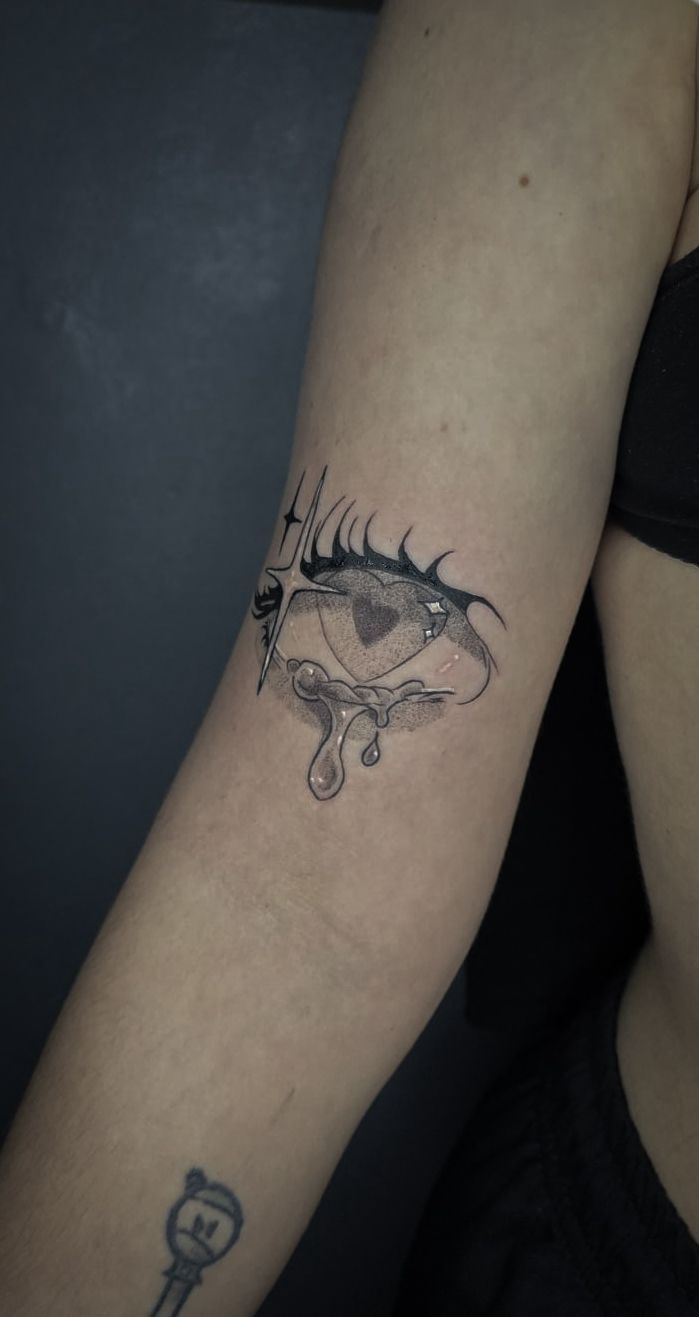 Primer plano de la parte superior de un brazo con un tatuaje negro que presenta un diseño celestial o decorativo.