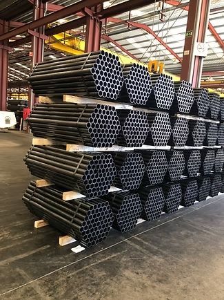 Un almacén lleno de muchos tubos negros apilados uno encima del otro.