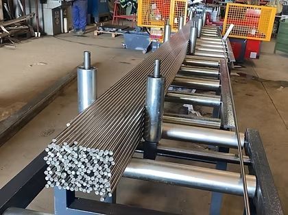 Un montón de varillas de metal están colocadas sobre una cinta transportadora en una fábrica.