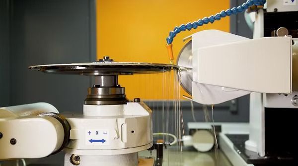 Una máquina está cortando un trozo de metal en una fábrica.
