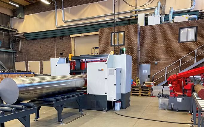 Una máquina corta un tubo grande de metal en una fábrica.