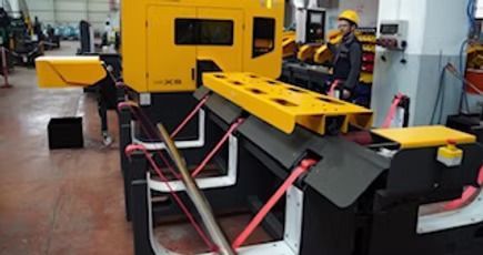 Un hombre está de pie junto a una máquina en una fábrica.