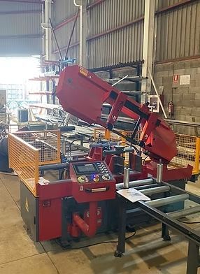 Una sierra de cinta roja está sobre una mesa en una fábrica.