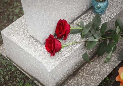 Dos rosas rojas están sentadas encima de una tumba.