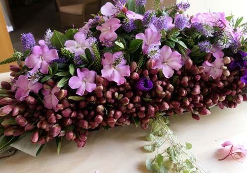 Un ramo de flores moradas está sobre una mesa.