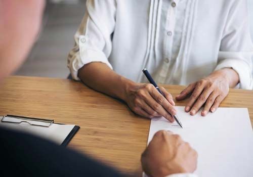 Un hombre y una mujer están sentados en una mesa escribiendo en un trozo de papel.