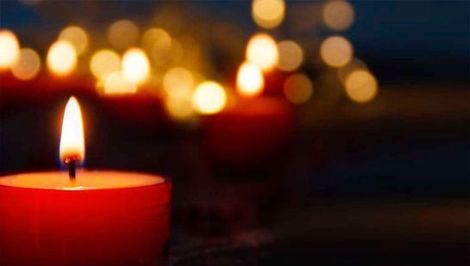 Un primer plano de una vela roja sobre una mesa con otras velas en el fondo.