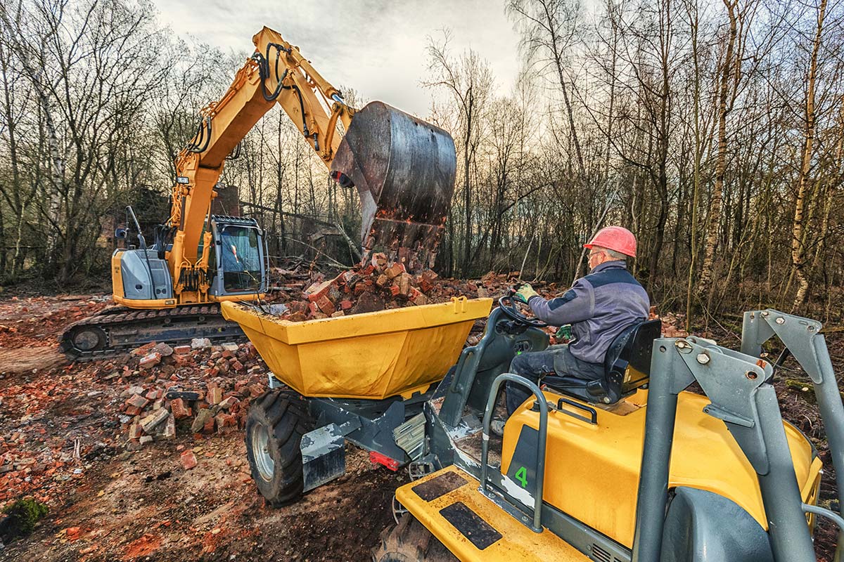 Un dumper et une pelleteuse sur le terrain qui ramassent des gravats