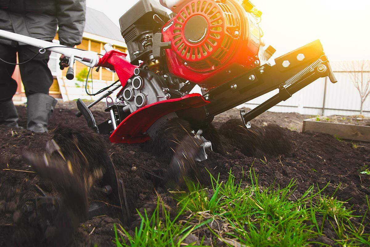 Gros plan sur un homme qui passe le motoculteur dans son jardin