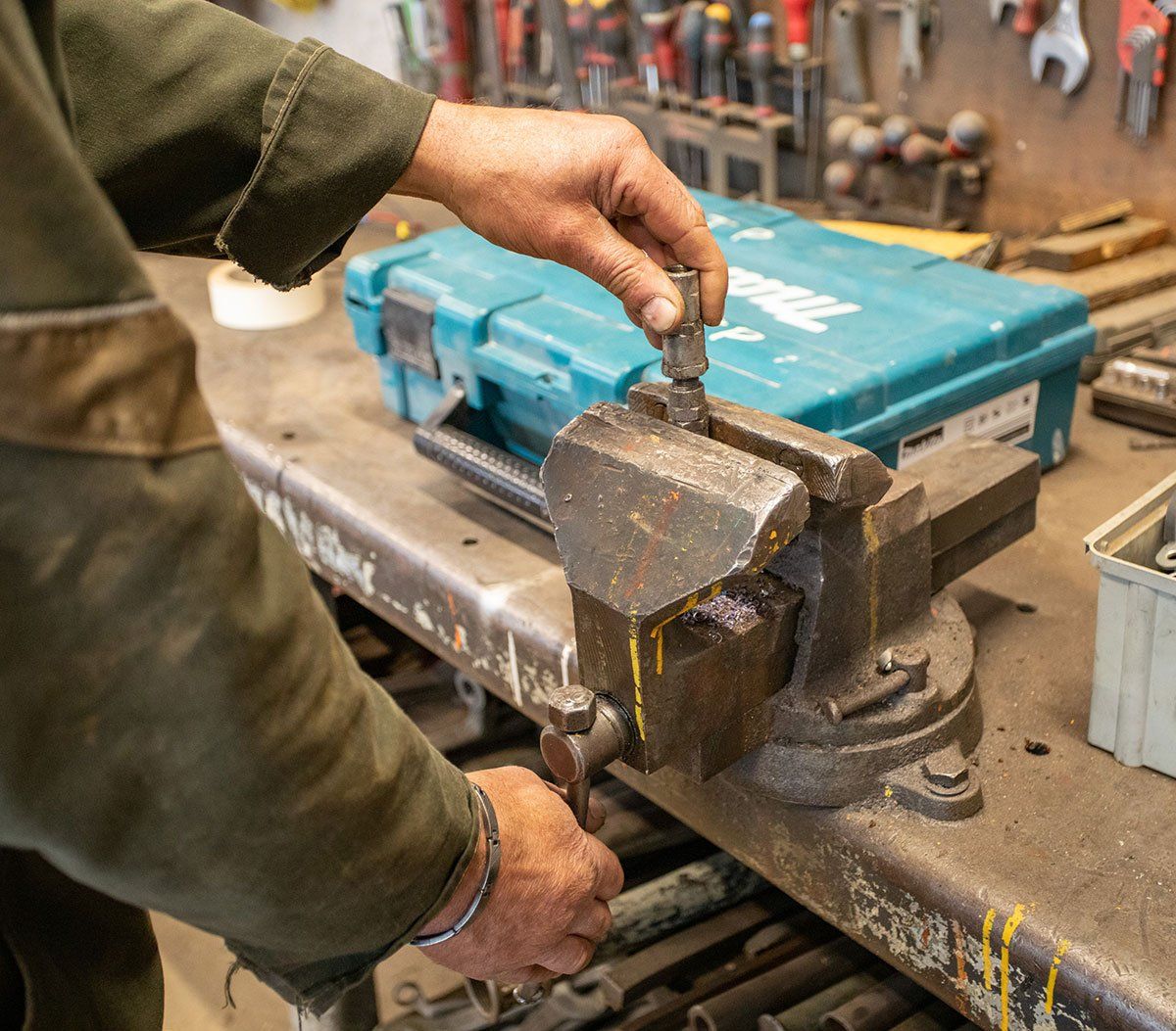 Un réparateur coince une pièce d'engin dans son étau
