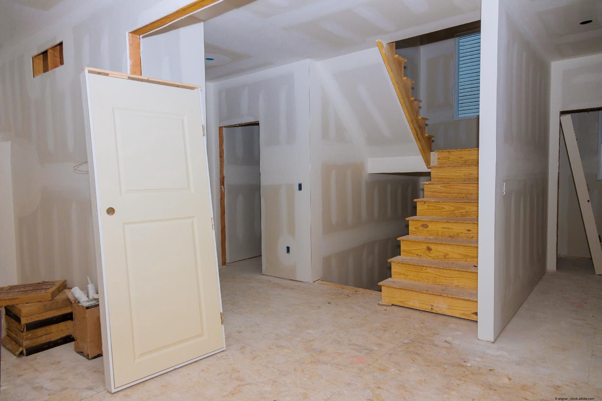 Innenraum im Ausbau mit neu installierter Holztreppe und unverputzten Wänden