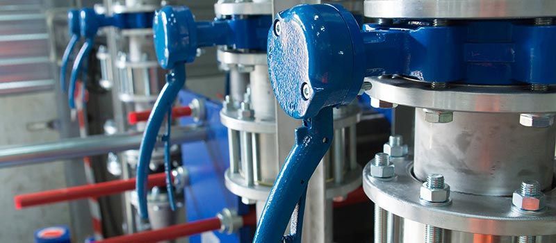 Vannes et tuyaux industriels bleus dans un environnement d'usine, gros plan sur des machines métalliques.