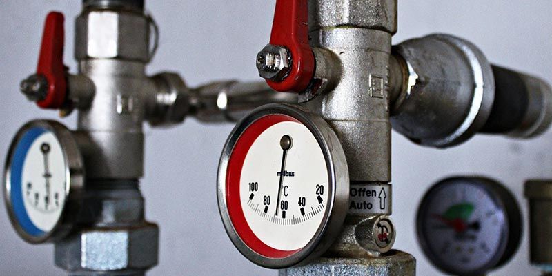Manomètres industriels et poignées de vannes rouges sur un système de tuyauterie métallique