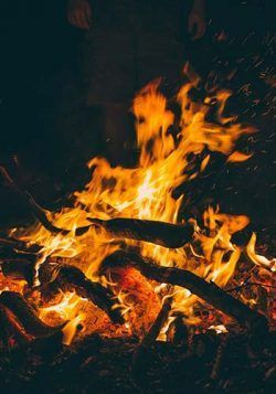 Bûches brûlant dans un feu de camp avec des flammes orange vif sur fond sombre