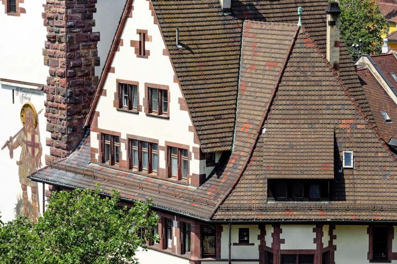 Bâtiment de style européen avec toits de tuiles pentus, murs blancs et cheminée au milieu des arbres