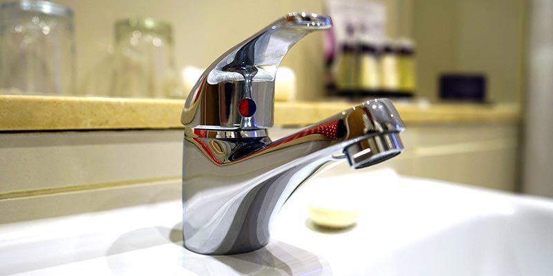 Robinet de salle de bain chromé au-dessus d'un lavabo blanc dans une salle de bain avec comptoir à l'éclairage tamisé