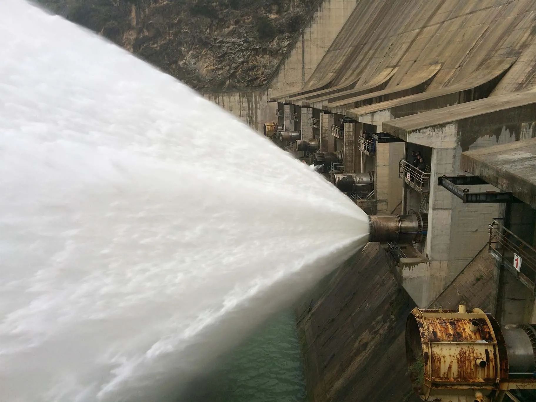 El agua brota con fuerza de una gran represa, creando un rocío blanco y espumoso.