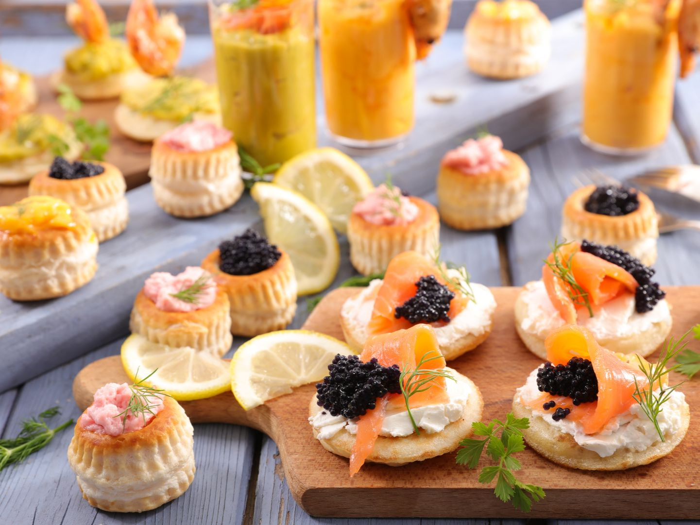 Un assortiment d'amuse-bouche composé de coques de pâte feuilletée, de saumon fumé, de caviar et de crème.
