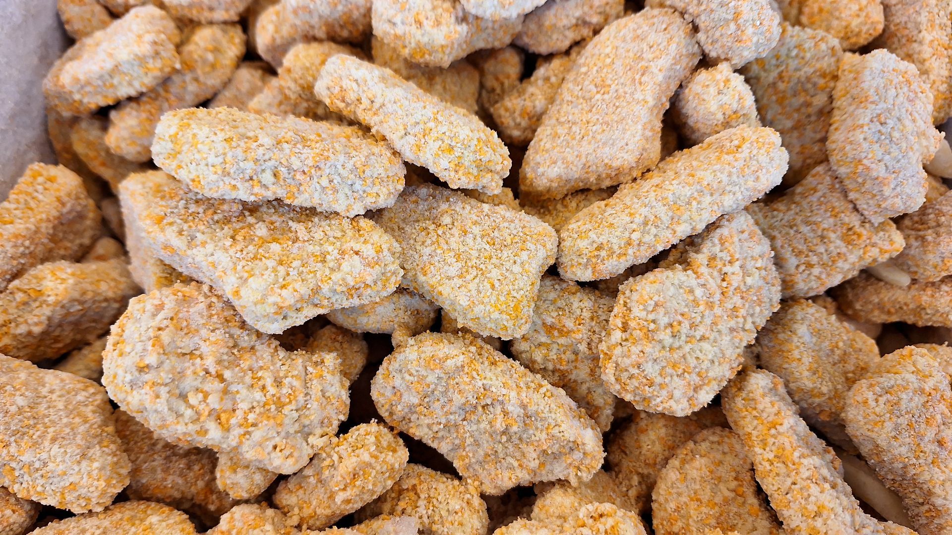 Gros plan sur un amas de nuggets de poulet panés et crus.