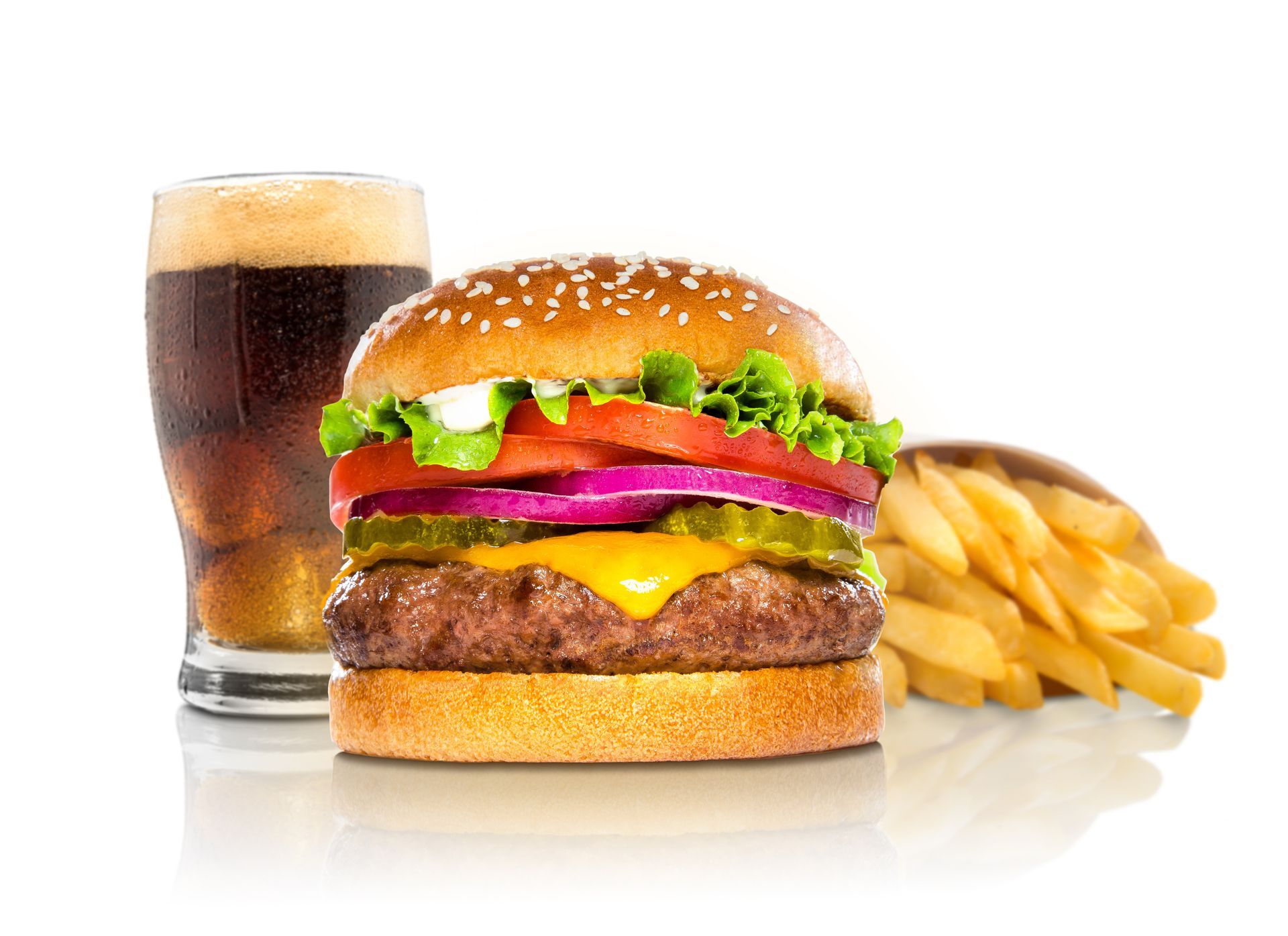 Un cheeseburger avec laitue, tomate et oignon, servi avec un verre de soda foncé et une portion de frites.