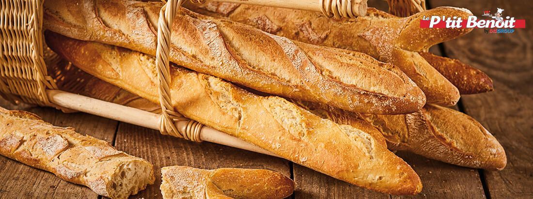 Des baguettes, des pains posés sur une table en bois.