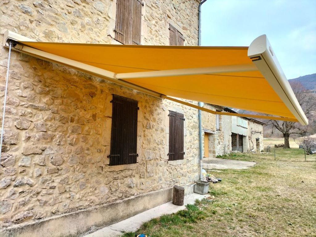 Store extérieur jaune, façade pierres apparentes