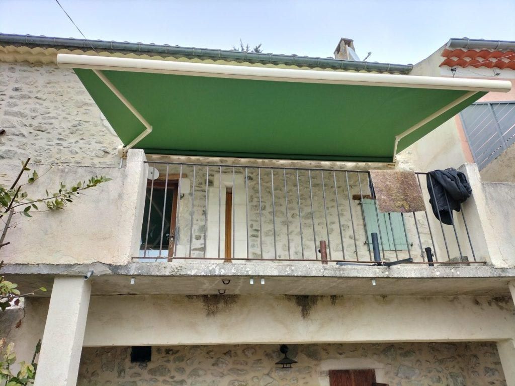 Store extérieur vert, façade pierres apparentes