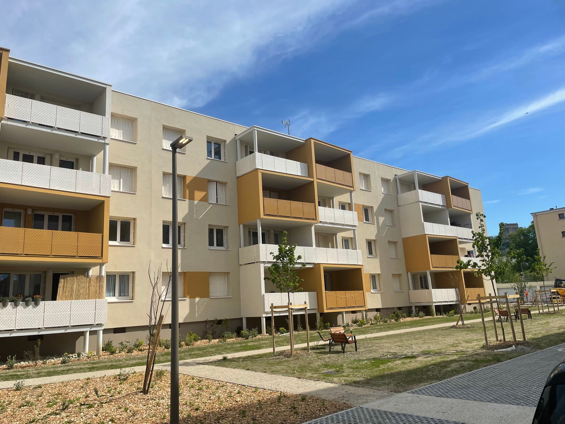 Immeuble d'appartements aux balcons et fenêtres jaunes, se détachant sur un ciel bleu.