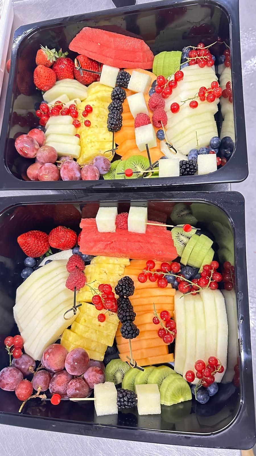 Hay dos bandejas de fruta sobre una mesa.