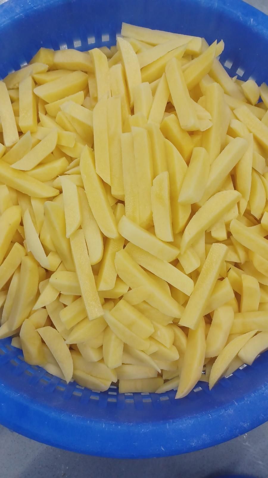 Un recipiente azul lleno de patatas fritas está sobre una mesa.