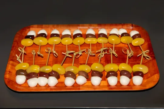 Una bandeja de madera llena de huevos y uvas en brochetas.