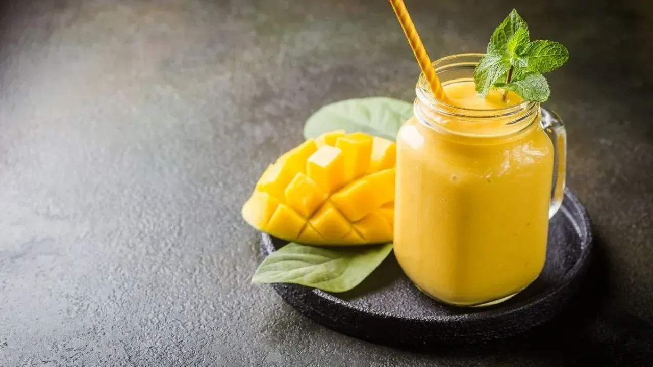Un batido de mango en un frasco de vidrio con una pajita.